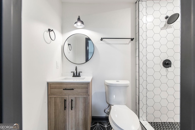 bathroom with tiled shower, toilet, and large vanity