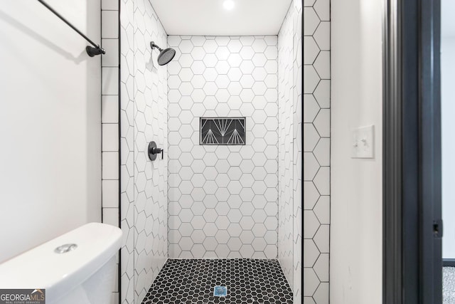 bathroom featuring toilet and a tile shower