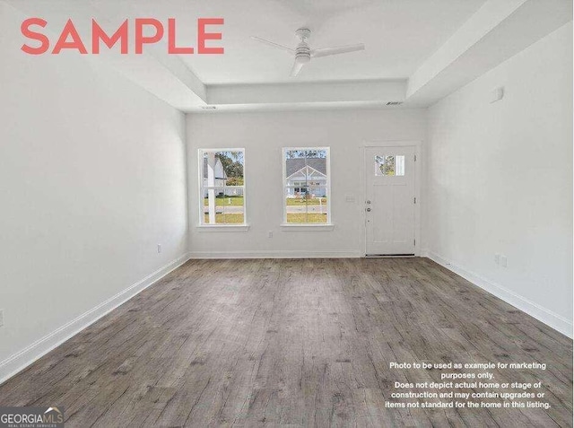 spare room with ceiling fan, a raised ceiling, and dark wood-type flooring