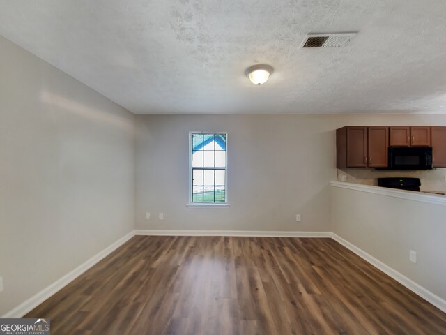 spare room featuring dark hardwood / wood-style flooring and a textured ceiling