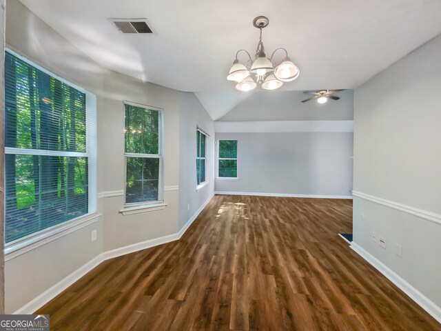 empty room featuring ceiling fan with notable chandelier, dark hardwood / wood-style floors, and vaulted ceiling