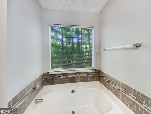 bathroom with a washtub and a textured ceiling