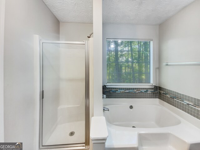 bathroom with separate shower and tub and a textured ceiling