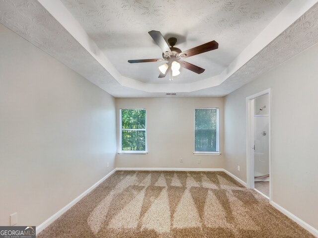 carpeted spare room featuring ceiling fan, a raised ceiling, and a textured ceiling