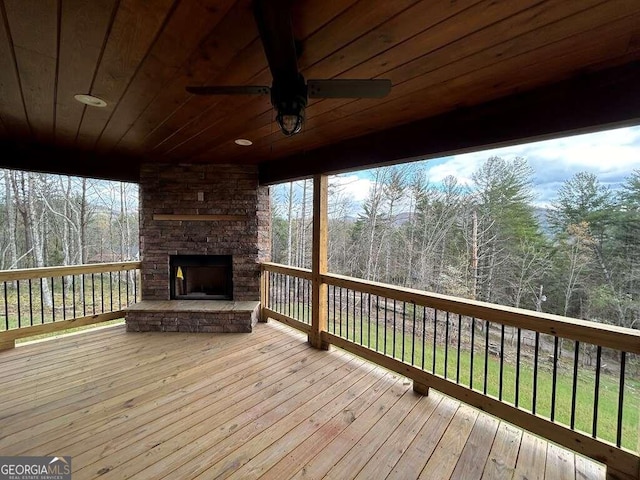 deck featuring an outdoor stone fireplace and ceiling fan