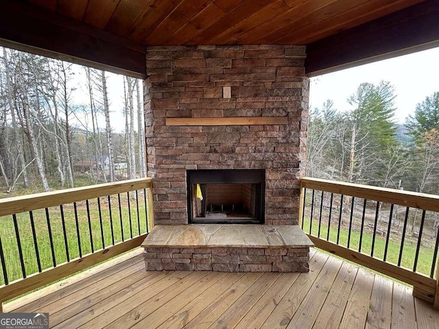 wooden terrace with an outdoor stone fireplace