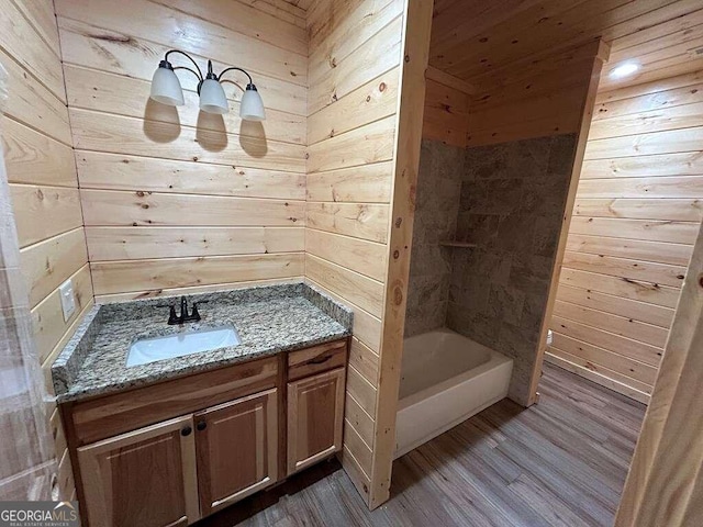 bathroom with hardwood / wood-style flooring, wooden walls, and vanity