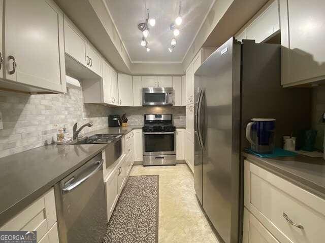 kitchen featuring white cabinetry, stainless steel appliances, sink, light tile floors, and tasteful backsplash