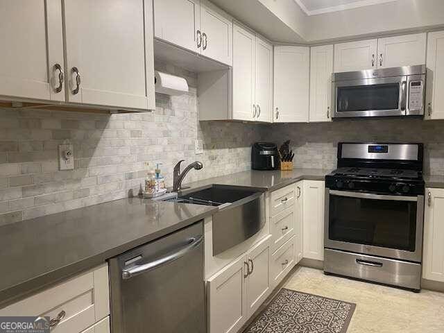 kitchen with appliances with stainless steel finishes, tasteful backsplash, sink, and white cabinetry