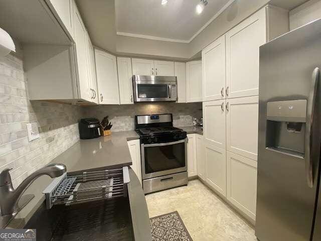 kitchen with light tile flooring, appliances with stainless steel finishes, backsplash, and white cabinetry