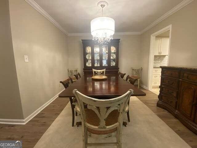 dining area with ornamental molding, light hardwood / wood-style flooring, and a chandelier