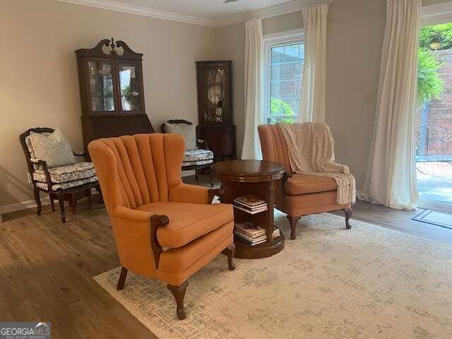 living area featuring hardwood / wood-style floors, a wealth of natural light, and crown molding