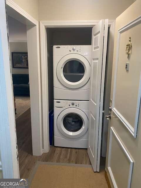 laundry room featuring wood-type flooring and stacked washer / dryer