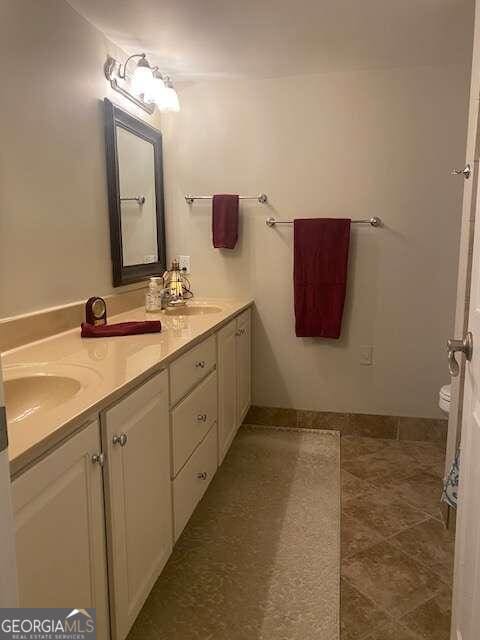 bathroom with oversized vanity, toilet, double sink, and tile flooring