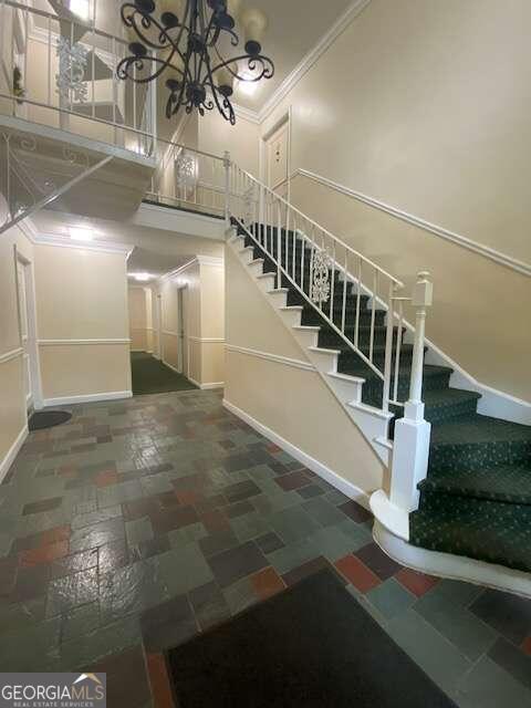 interior space with a chandelier, crown molding, and tile flooring