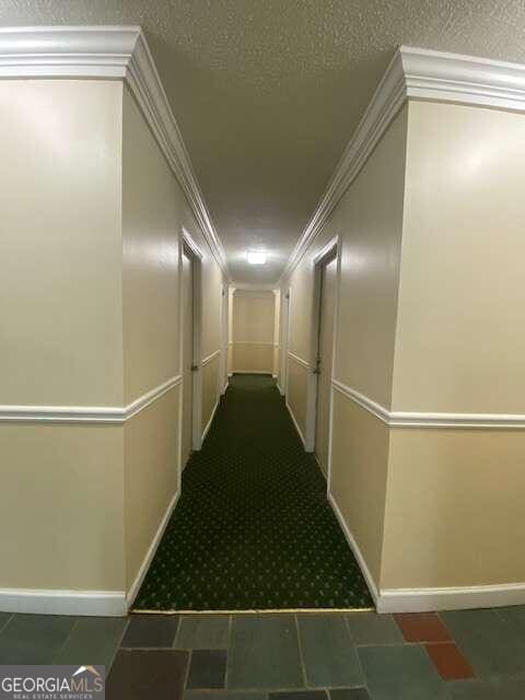 corridor with ornamental molding, tile flooring, and a textured ceiling