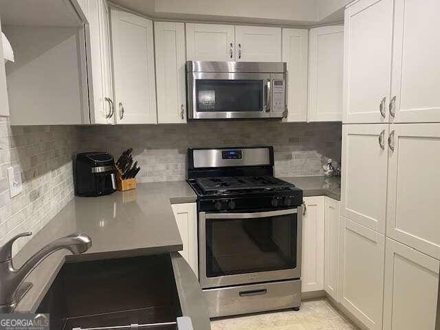 kitchen featuring appliances with stainless steel finishes, tasteful backsplash, sink, and white cabinetry