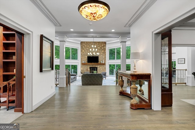 entryway featuring ornate columns, a stone fireplace, and hardwood / wood-style flooring