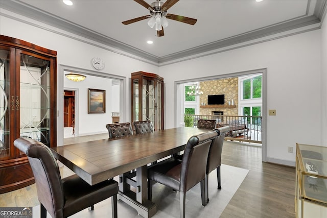 dining space featuring ornamental molding, a fireplace, wood-type flooring, and ceiling fan