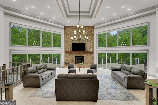 tiled living room with plenty of natural light, a tray ceiling, a notable chandelier, and a stone fireplace