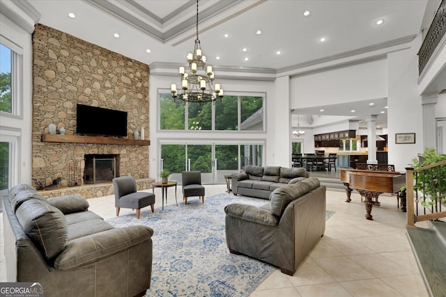 living room with a stone fireplace, a healthy amount of sunlight, and a towering ceiling