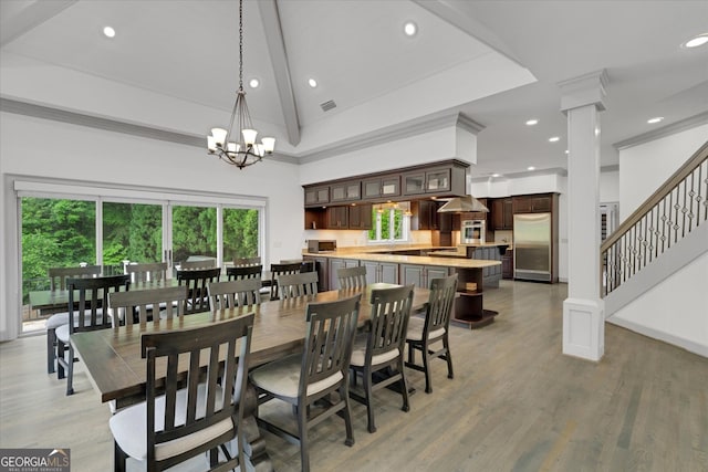 dining space featuring a chandelier, light hardwood / wood-style flooring, beam ceiling, high vaulted ceiling, and ornate columns