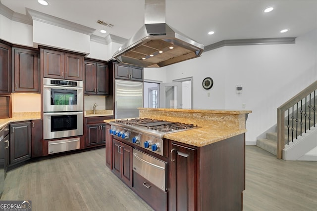 kitchen with light hardwood / wood-style floors, a kitchen island, island range hood, stainless steel appliances, and light stone counters