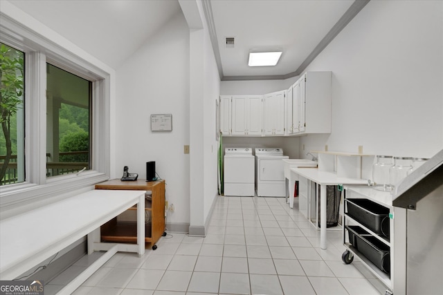 laundry area with washing machine and clothes dryer, cabinets, and light tile floors