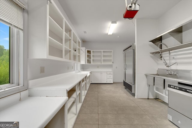 interior space with dishwasher, white cabinets, and light tile floors