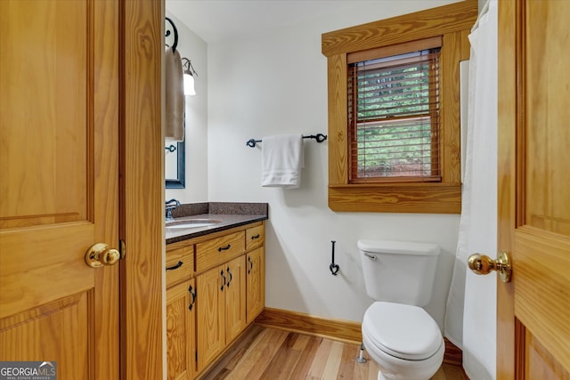 bathroom with hardwood / wood-style flooring, toilet, and vanity