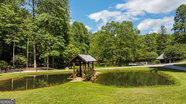 surrounding community with a gazebo, a lawn, and a water view