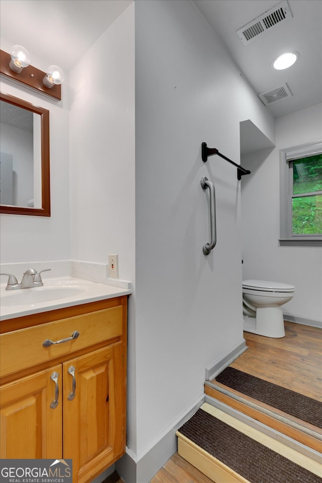 bathroom featuring wood-type flooring, vanity, and toilet