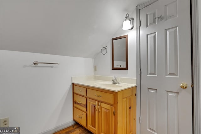 bathroom featuring hardwood / wood-style flooring, lofted ceiling, and oversized vanity