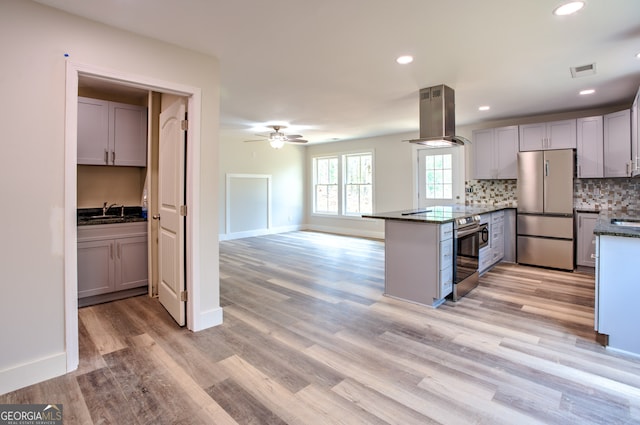 kitchen featuring kitchen peninsula, island exhaust hood, gray cabinets, appliances with stainless steel finishes, and light hardwood / wood-style floors