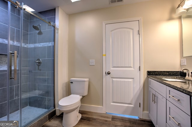 bathroom with wood-type flooring, vanity, walk in shower, and toilet