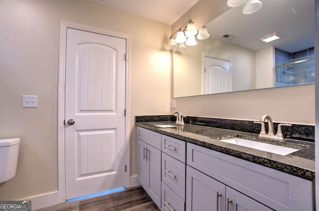 bathroom with wood-type flooring, walk in shower, vanity, and toilet