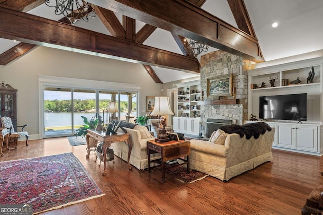 living room with a water view, high vaulted ceiling, built in shelves, and a fireplace