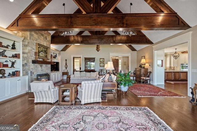 living room featuring dark wood-type flooring, built in features, vaulted ceiling with beams, and a stone fireplace