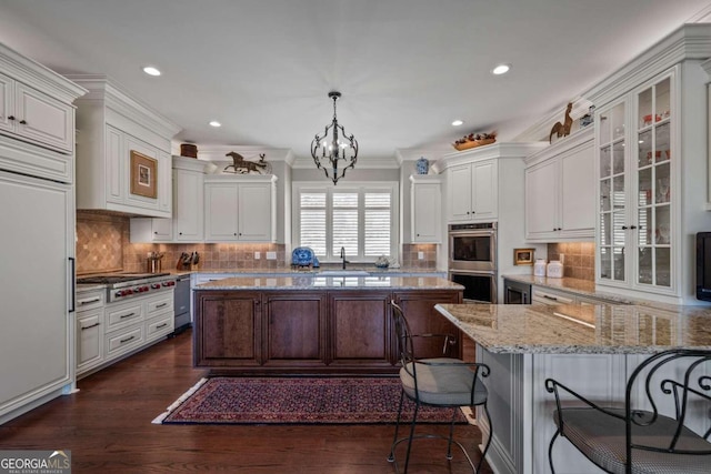 kitchen featuring an inviting chandelier, light stone counters, hanging light fixtures, dark hardwood / wood-style floors, and appliances with stainless steel finishes