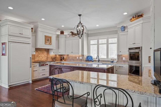 kitchen featuring stainless steel appliances, decorative light fixtures, light stone counters, kitchen peninsula, and crown molding