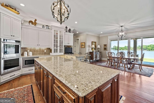 kitchen featuring stainless steel appliances, white cabinets, a center island, and decorative light fixtures