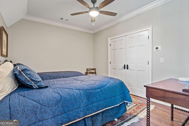 bedroom with lofted ceiling, ceiling fan, hardwood / wood-style flooring, a closet, and crown molding