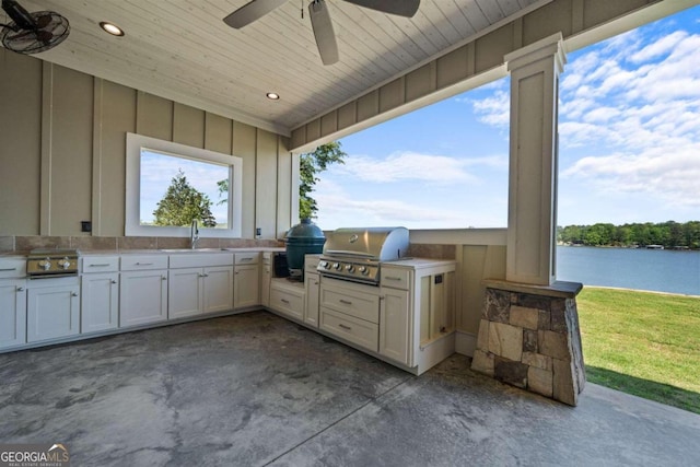 view of patio / terrace featuring sink, a water view, exterior kitchen, and grilling area