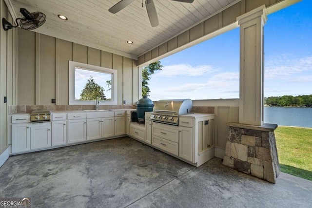 view of patio / terrace with sink, a water view, grilling area, ceiling fan, and exterior kitchen