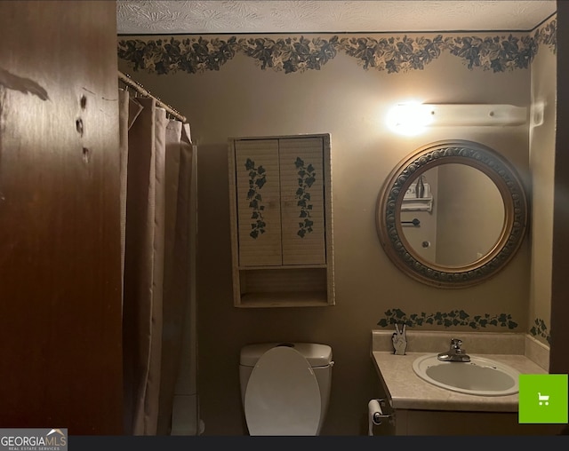 bathroom with a textured ceiling, vanity, and toilet