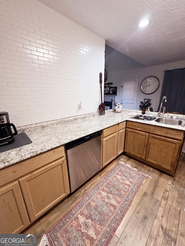 kitchen with lofted ceiling, sink, wood-type flooring, a textured ceiling, and stainless steel dishwasher