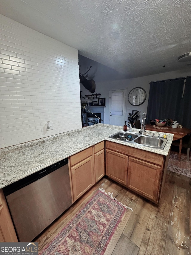 kitchen featuring sink, a textured ceiling, kitchen peninsula, dishwasher, and hardwood / wood-style floors