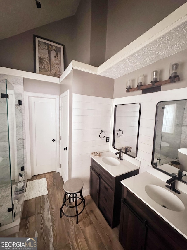 bathroom featuring wood-type flooring, vaulted ceiling, vanity, and walk in shower