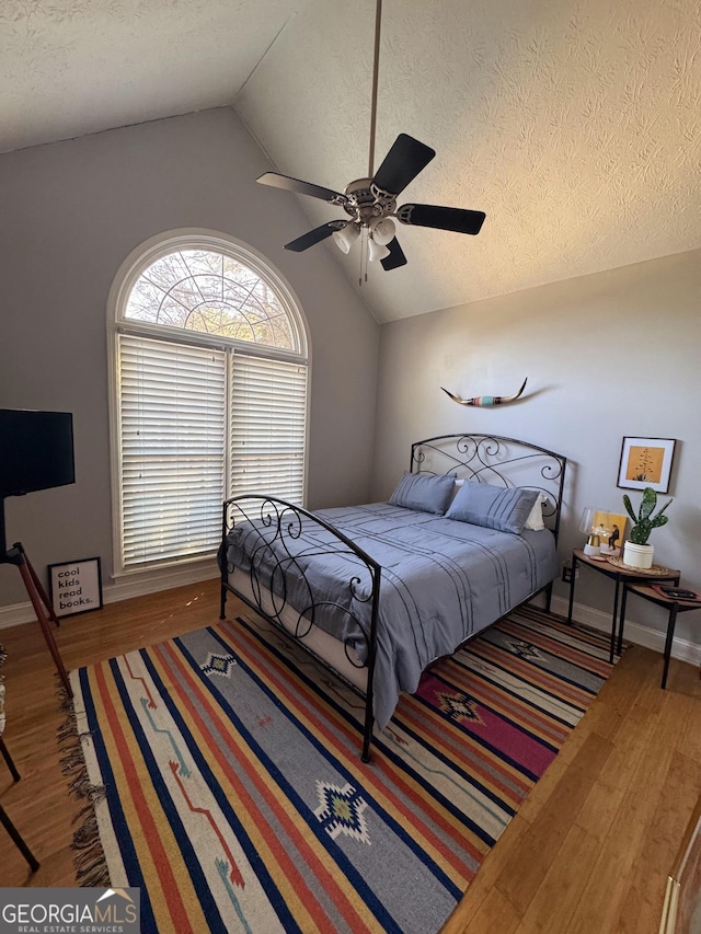 bedroom featuring vaulted ceiling, ceiling fan, hardwood / wood-style floors, and a textured ceiling