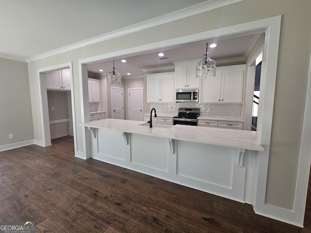 kitchen with dark wood-type flooring, hanging light fixtures, stainless steel appliances, a breakfast bar, and white cabinets